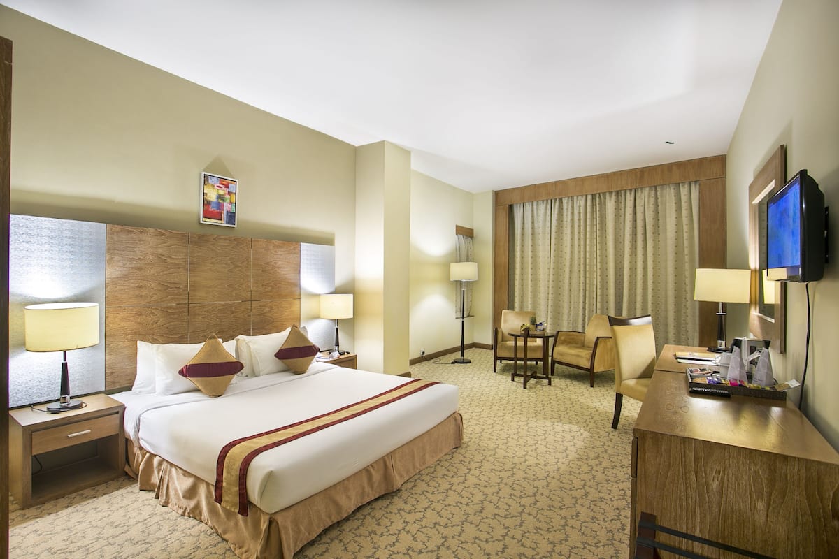 Une chambre d’hôtel avec un grand lit, un bureau, une chaise et un téléviseur.