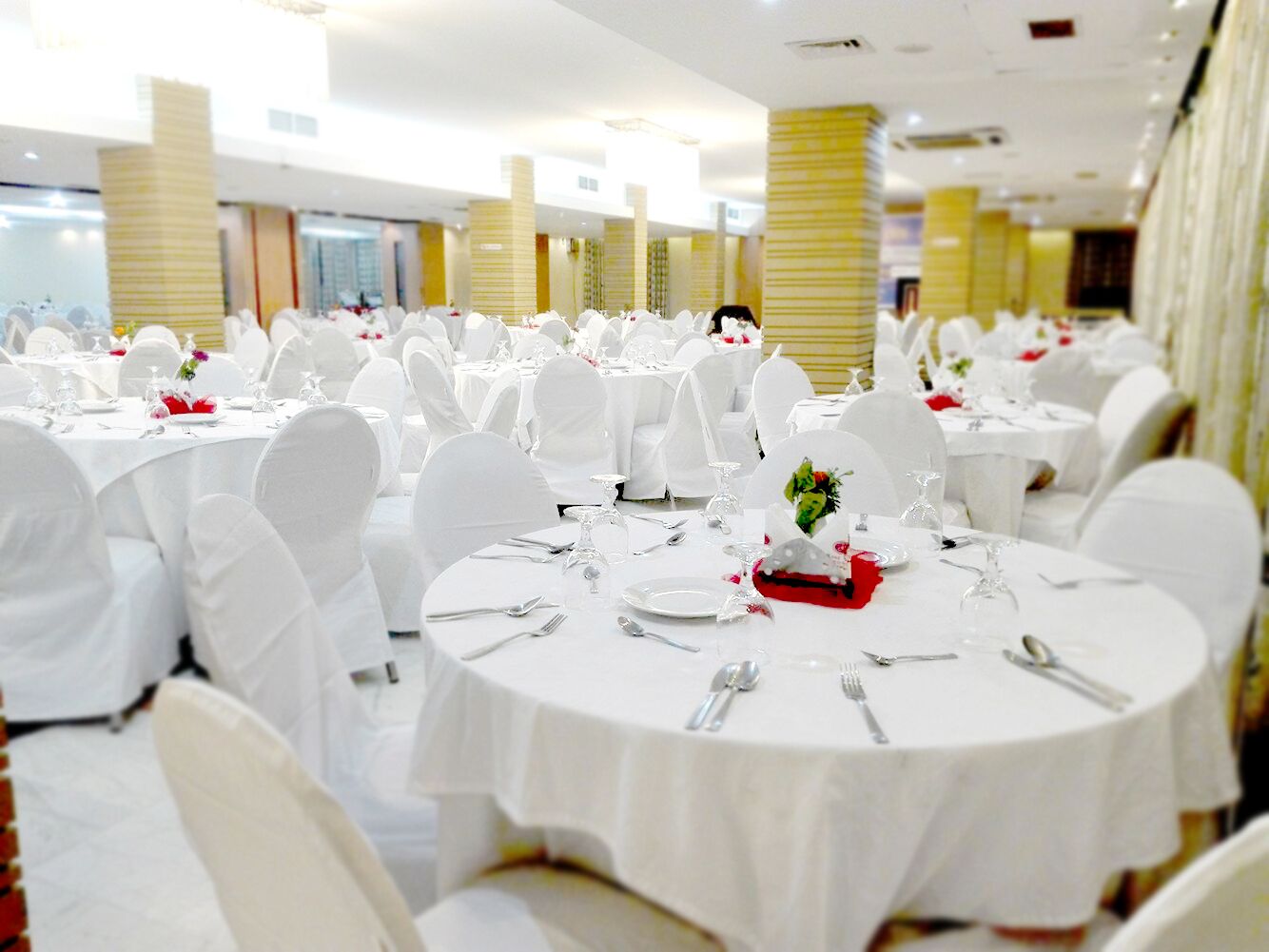A banquet hall with round tables set for dining, white chairs, and a clean, organized layout.