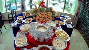 A buffet table with various dishes and drinks, surrounded by chairs and a window view. - Rose View Hotel (Sylhet)