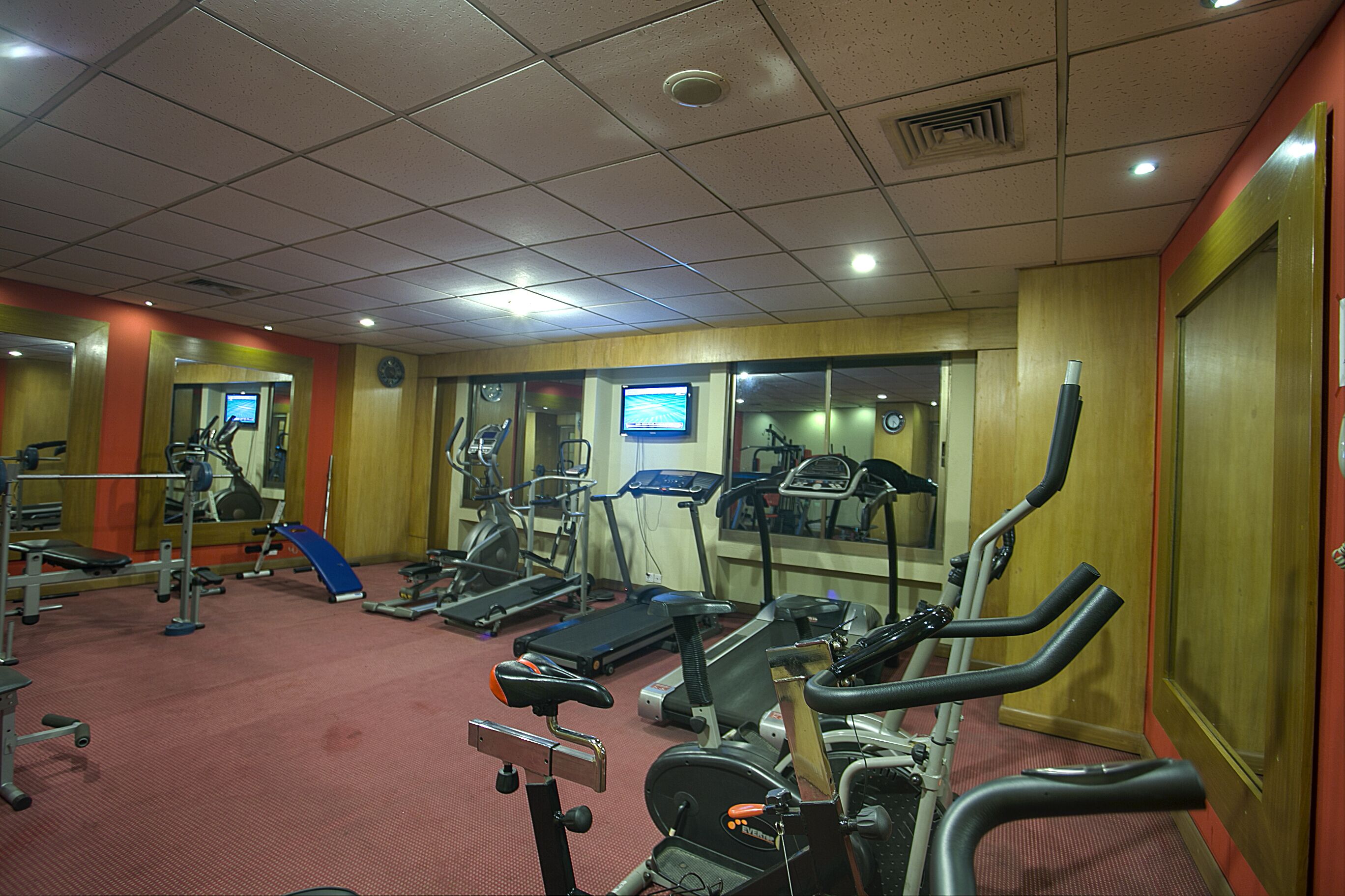 Un gimnasio con cintas de correr, elípticas y equipo de pesas.