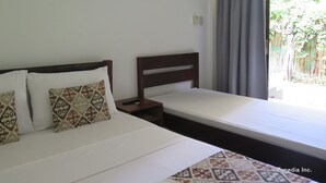Een slaapkamer met een bed, twee kussens, een nachtkastje en een raam met gordijnen.