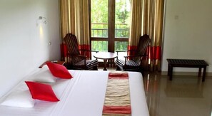 A hotel room with a bed, two chairs, a small table, and a bench. - Magampura Eco Village Resort (Thissamaharama)