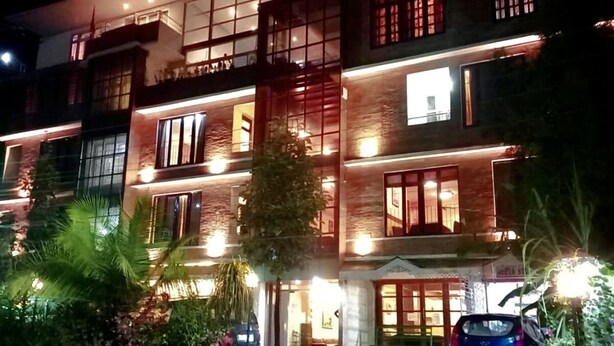 A multi-story building with balconies and large windows, surrounded by greenery. - Maya Inn (Gangtok)