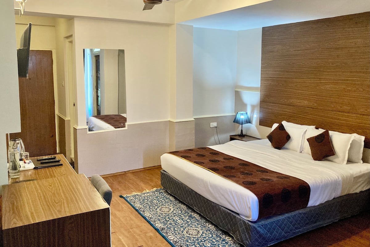 A hotel room with a bed, bedside table, lamp, and a ceiling fan.