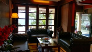 A lobby with two leather sofas, a glass coffee table, and a decorative vase. - Maya Inn (Gangtok)