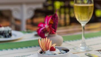 A dessert on a white plate with a glass of white wine beside it, set on a table with a patterned tablecloth.
