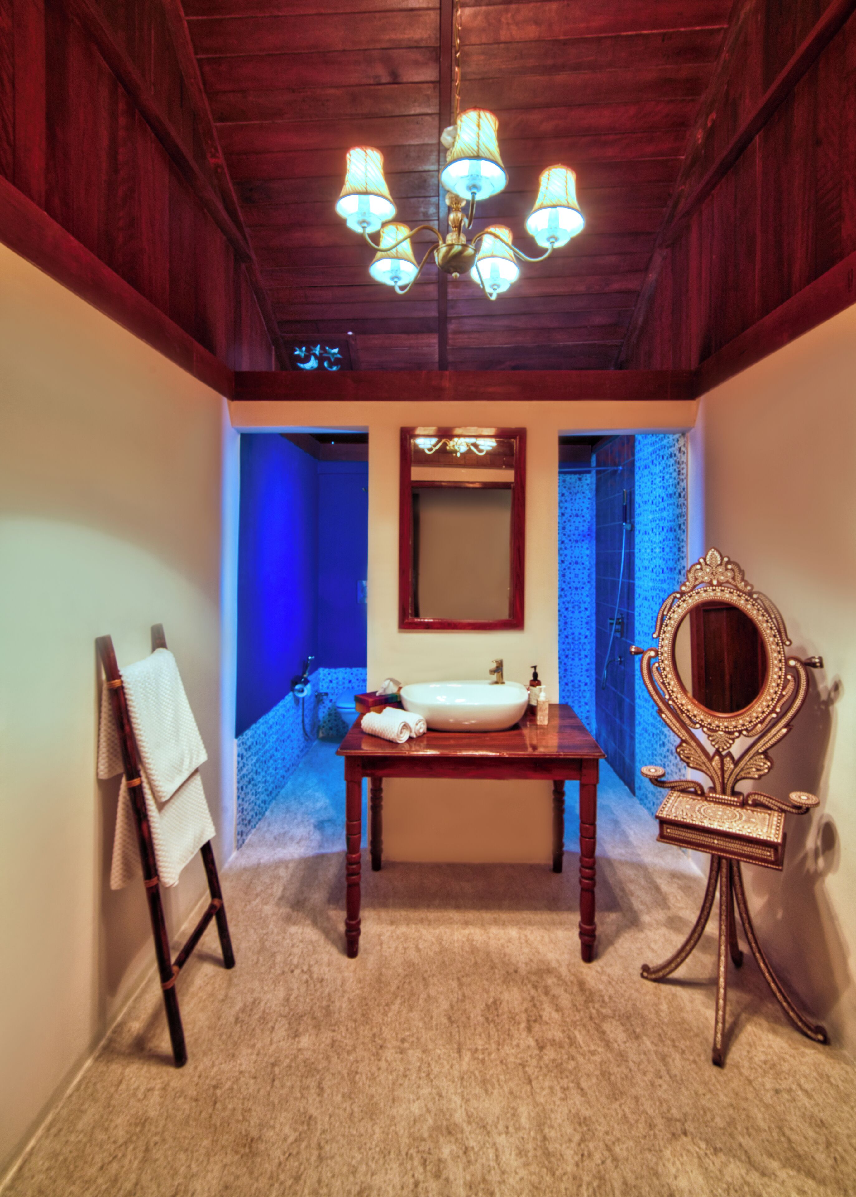 Un baño con tocador de madera, lavamanos, espejo y candelabro.