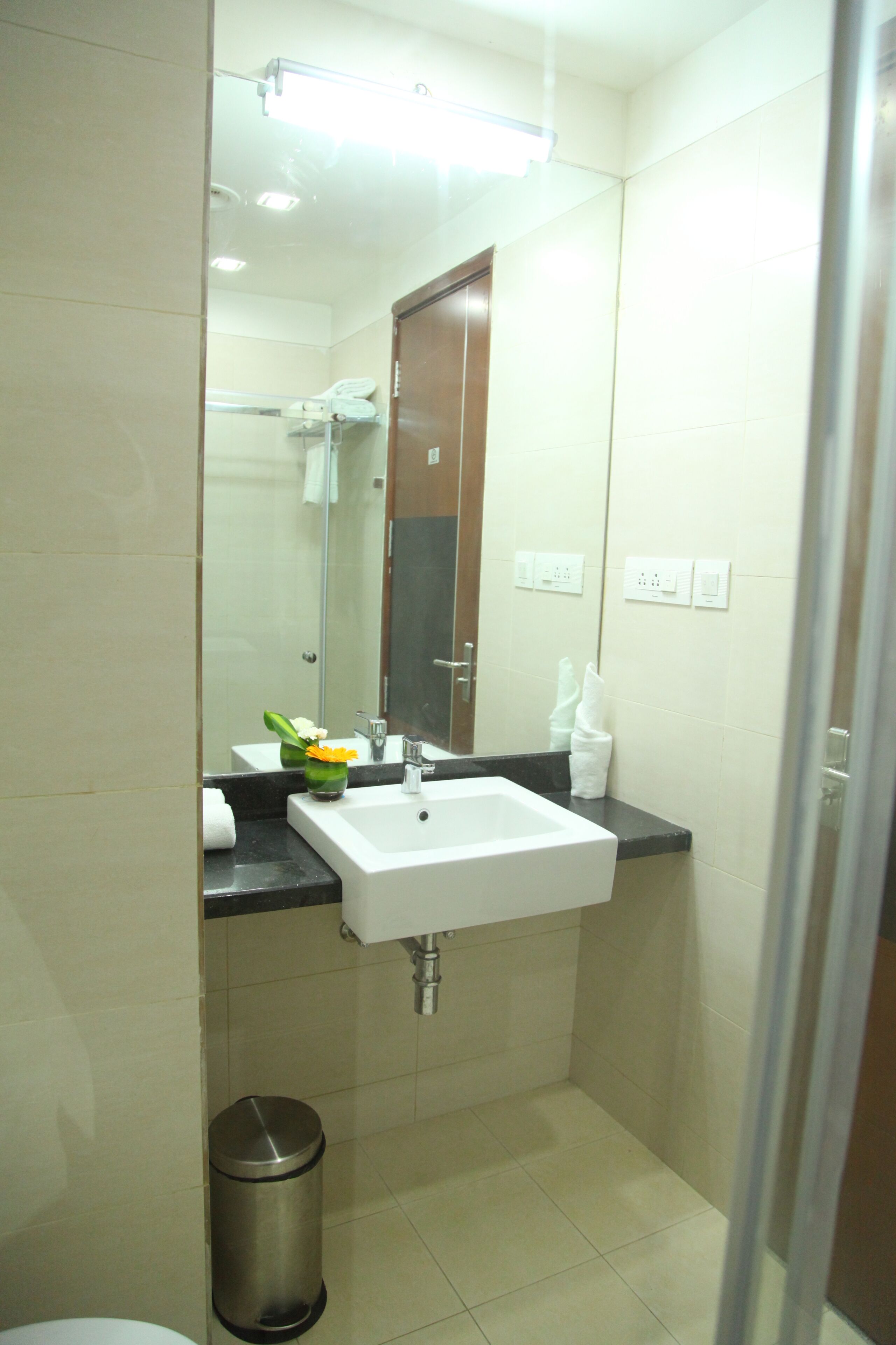A bathroom with a white sink, a mirror, a towel rack, and a trash bin.