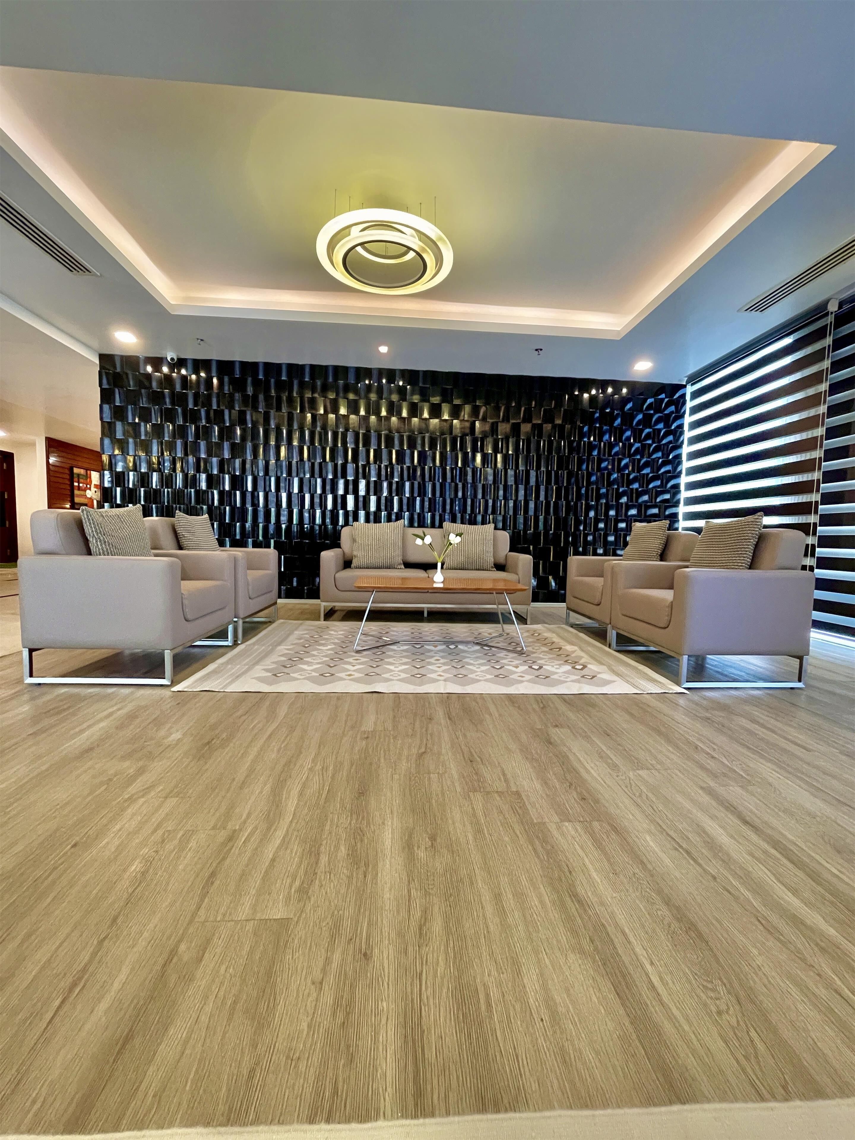 Uma sala de estar moderna com um sofá, uma mesa de centro e um painel decorativo na parede.