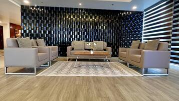 Uma sala de estar moderna com um sofá, uma mesa de centro e um painel decorativo na parede.