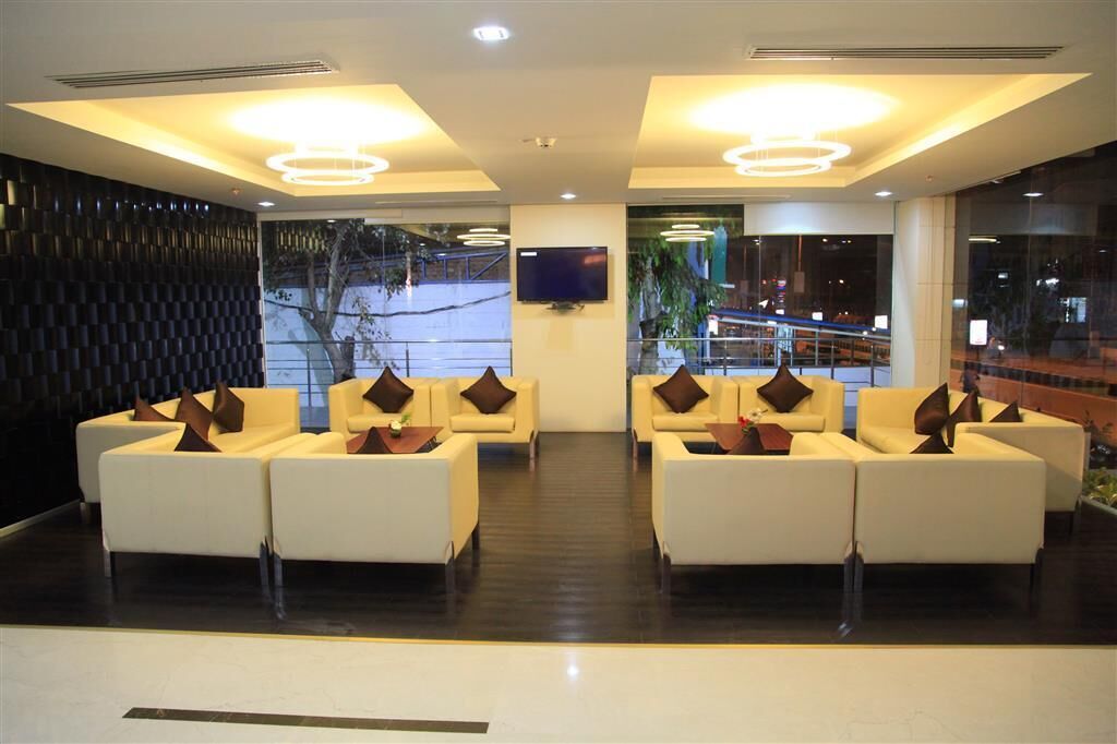 A lobby with a modern design, featuring a seating area with sofas and a flat-screen TV mounted on the wall.