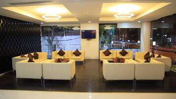 A lobby with a modern design, featuring a seating area with sofas and a flat-screen TV mounted on the wall.