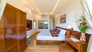 A hotel room with a wooden bed, a wooden wardrobe, a bedside table, a bench, and a vase with flowers. - Lakeview Villa Homestay Hoi An (Da Nang)