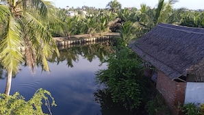 A calm water body with palm trees and a thatched-roof structure. - Lakeview Villa Homestay Hoi An (Da Nang)