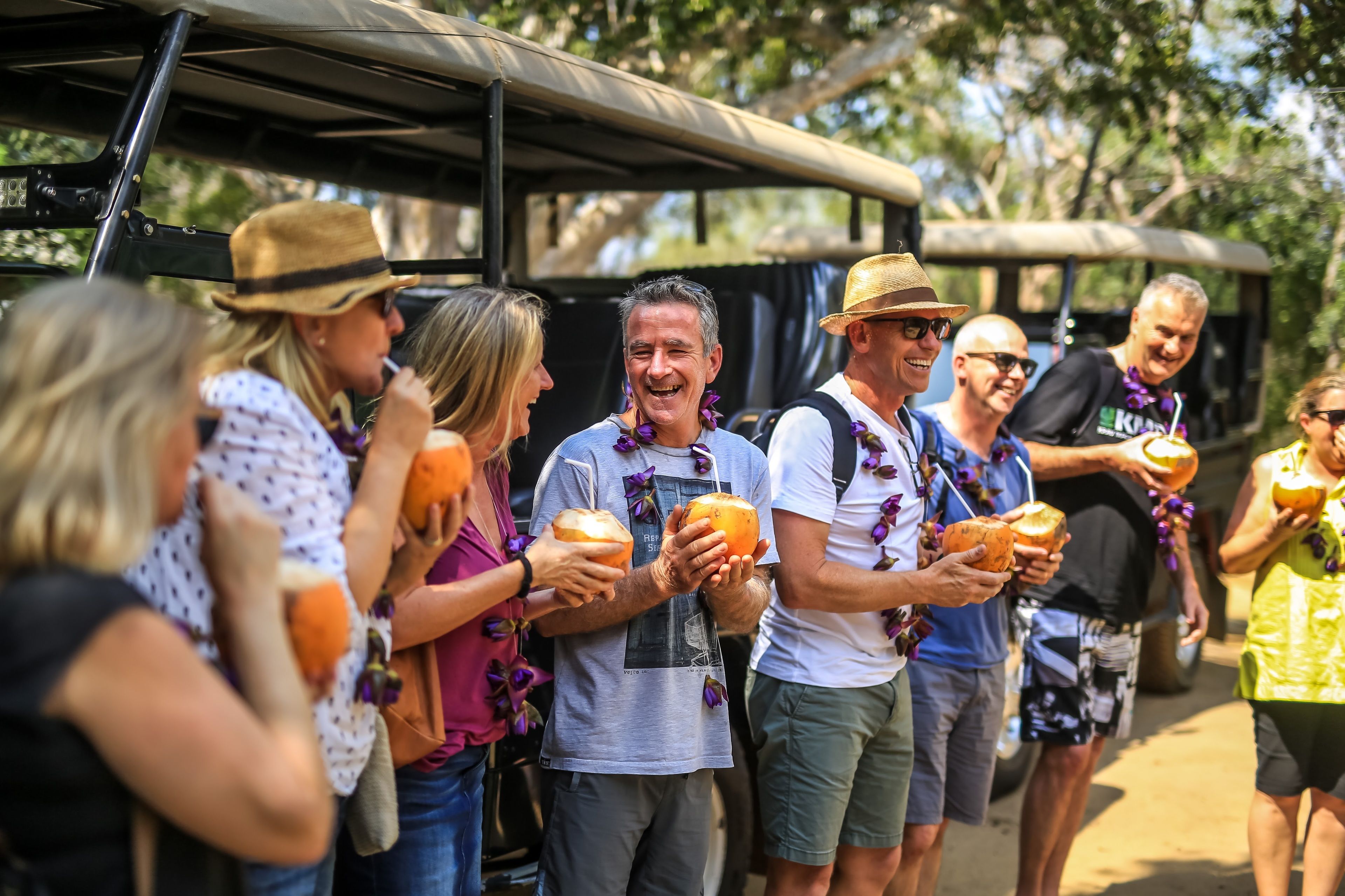 A group of people standing outdoors, holding coconuts.