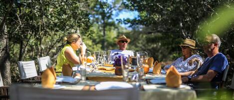 A group of people dining outdoors at a table set with various dishes and drinks.
