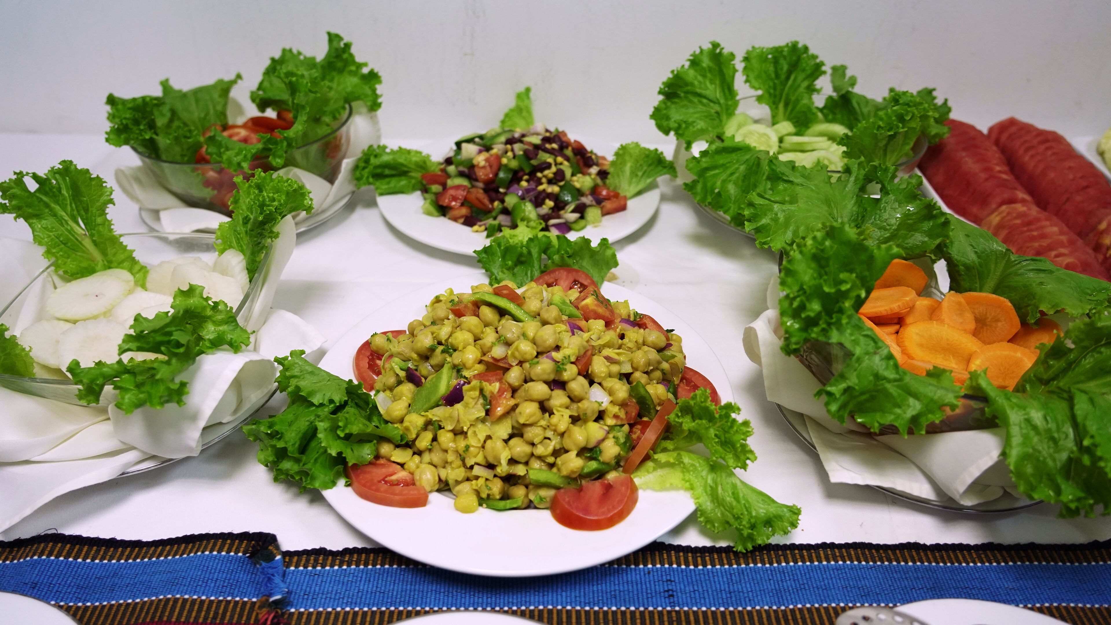 Una mesa con ensaladas y verduras variadas, como lechuga, tomates y zanahorias.