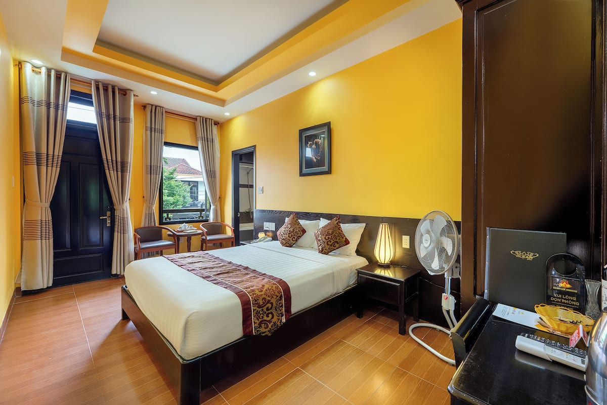 A hotel room with a large bed, bedside tables, a desk, and a chair.