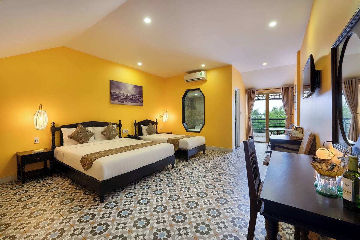 A hotel room with two beds, a dining table, and a large window with curtains.