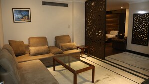 Una sala de estar con un sofá, una mesa de centro de vidrio y un biombo decorativo.