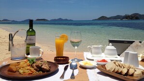A table set with breakfast items, a bottle of wine, and a view of the sea.