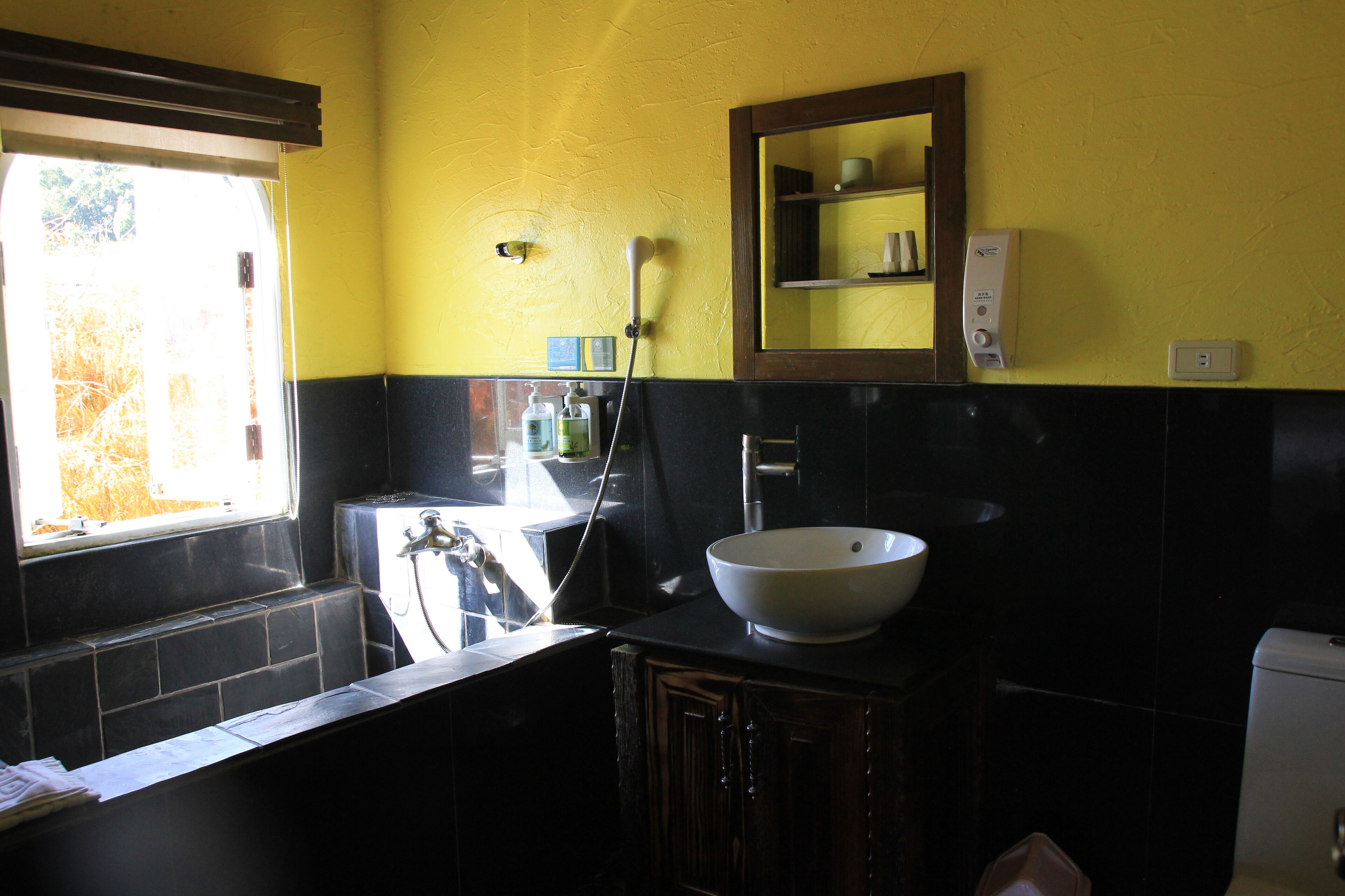 A bathroom with a large window, a sink, a mirror, and a shower.