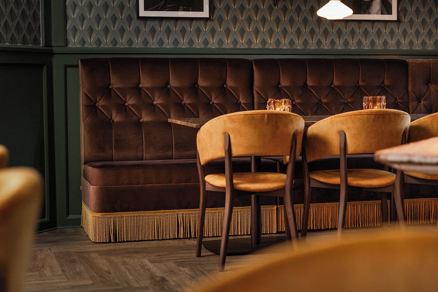 L’intérieur d’un restaurant présente un canapé marron capitonné, des chaises jaunes et un panier tressé à la base.