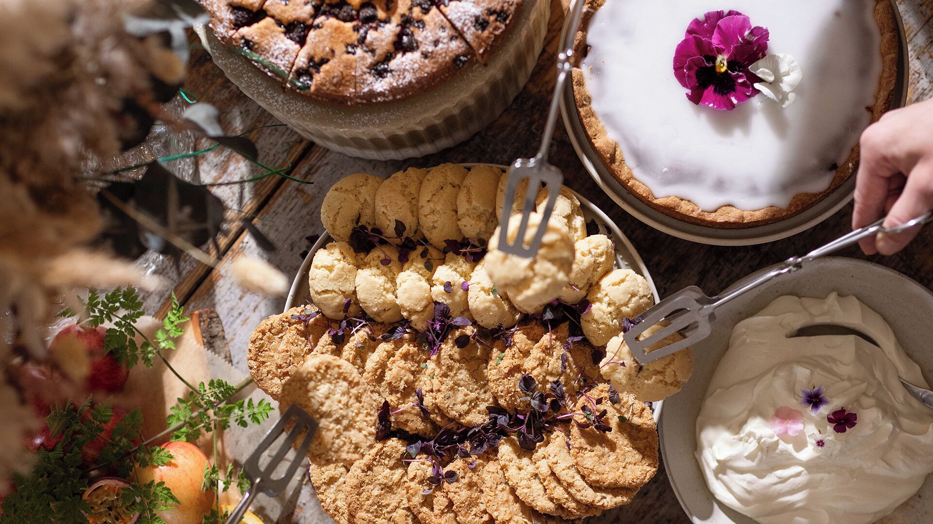 Diversos doces, incluindo tortas, biscoitos e sorvete, com uma pessoa servindo sorvete.