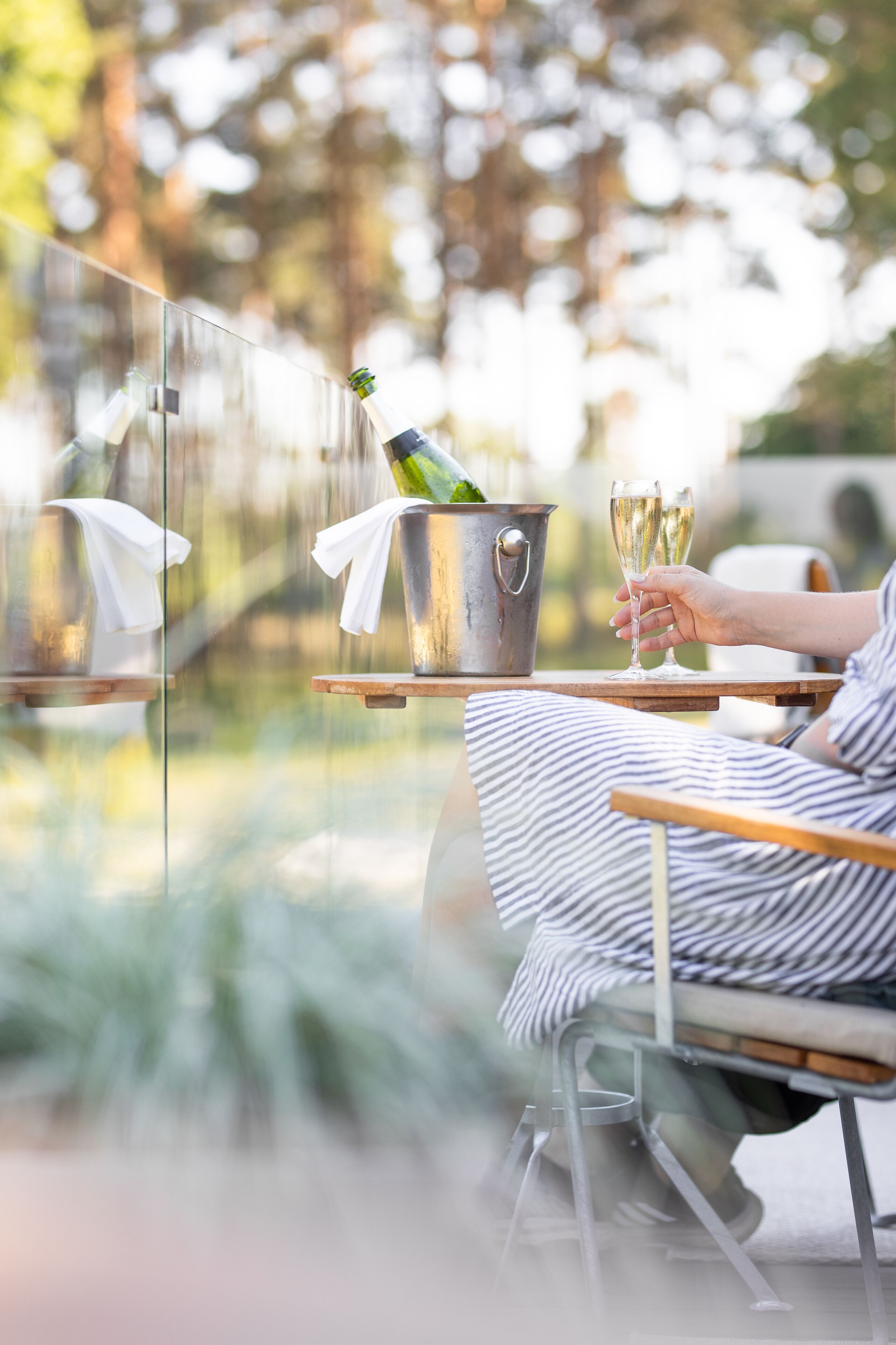 A person seated at a table with a glass of champagne and a bottle of champagne in a bucket.