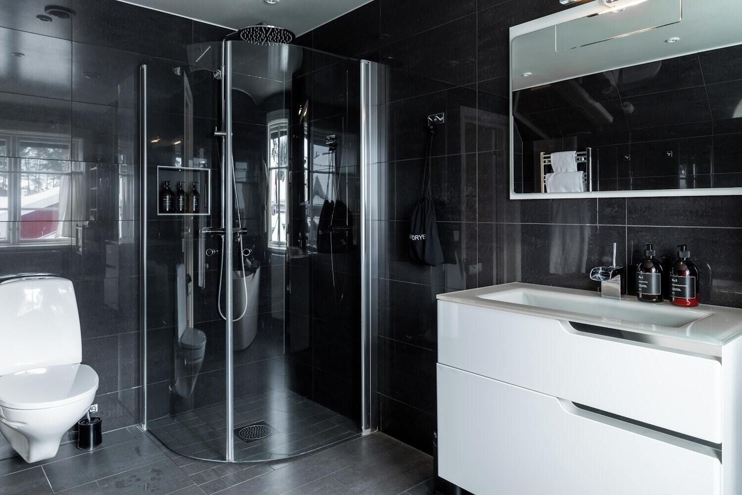 Un baño moderno con ducha envuelta en vidrio, un lavabo blanco y un espejo encima.