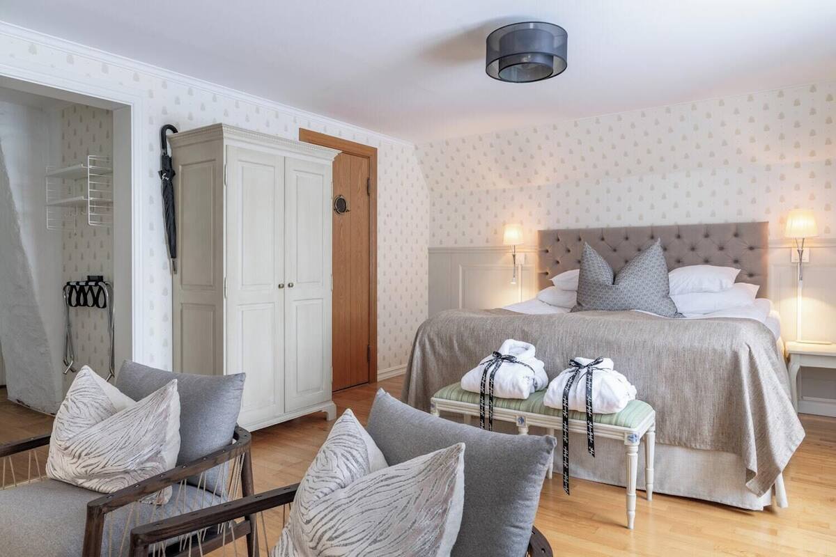 A bedroom with a bed, bedside tables, a chair, a wardrobe, and a door.