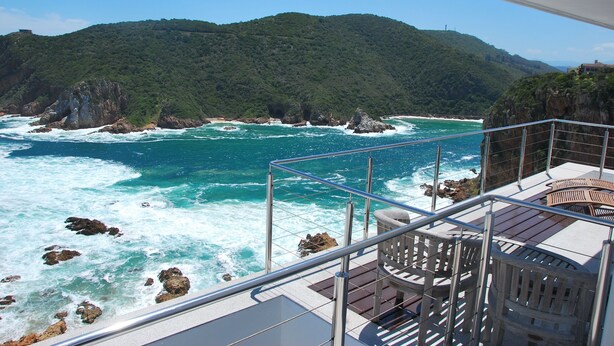 A balcony with a view of the ocean and a mountainous landscape.