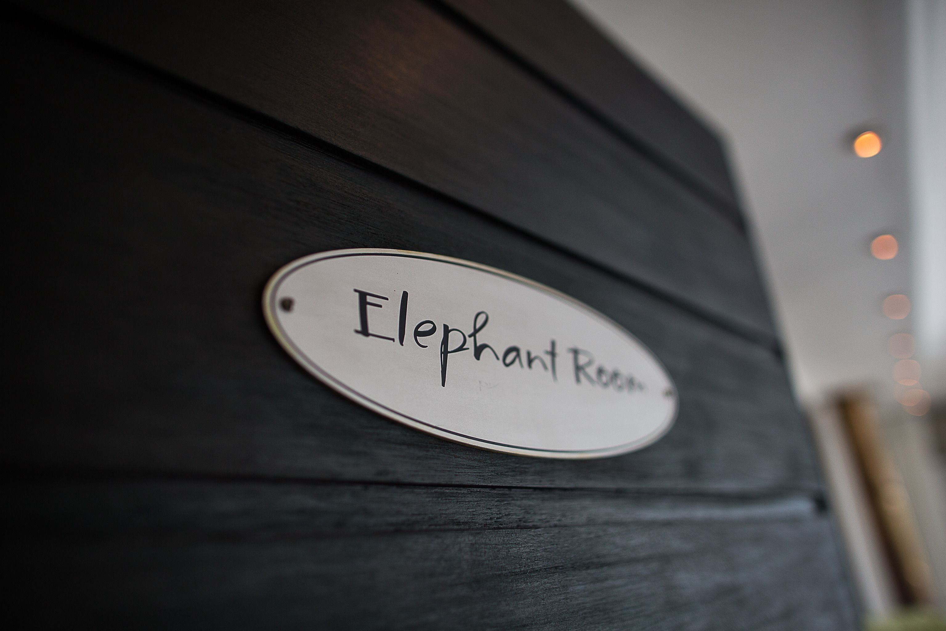 Un letrero sobre una superficie de madera oscura que dice 'Elephant Room'.