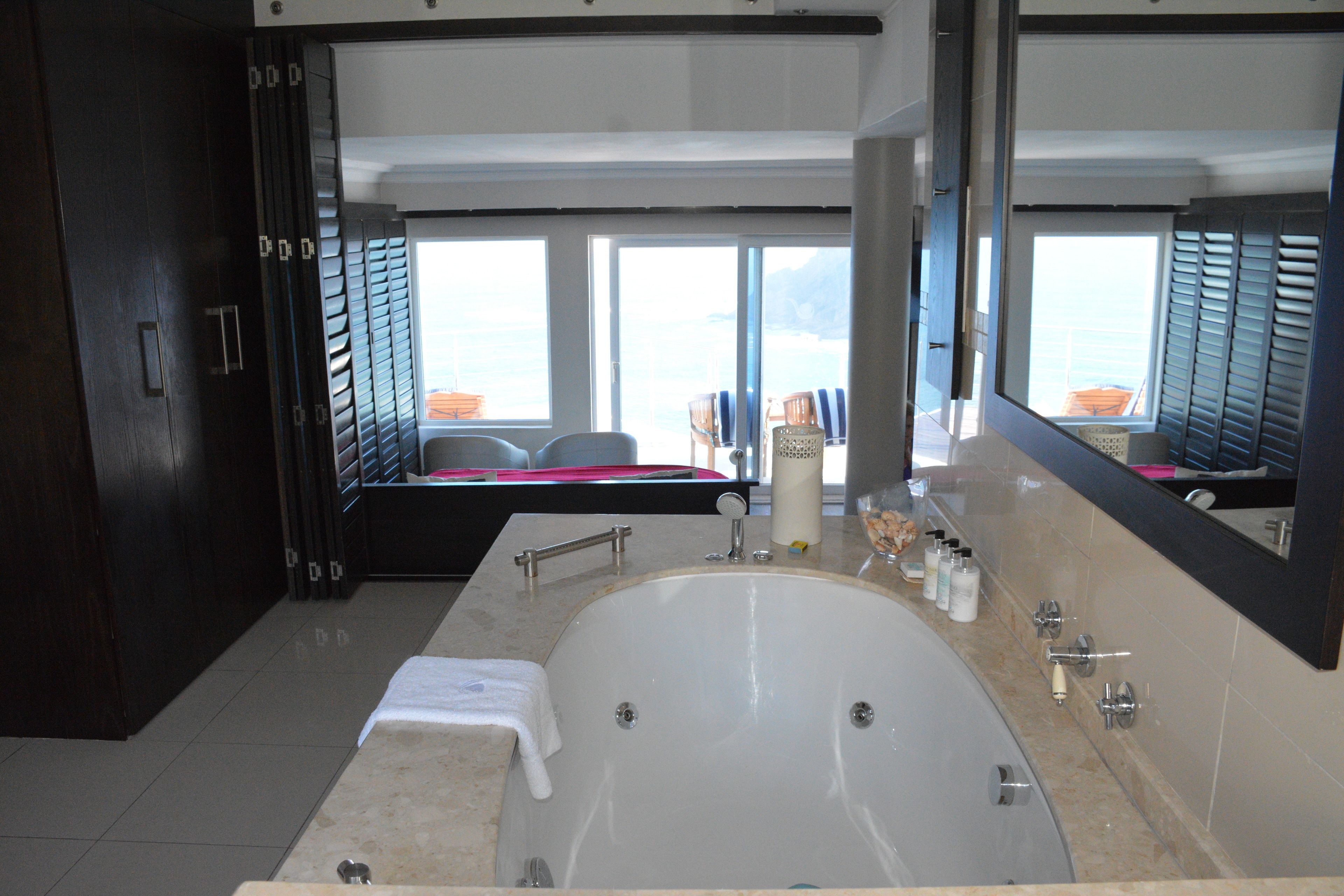 Une salle de bain moderne avec une grande baignoire, un double vasque et un grand miroir.
