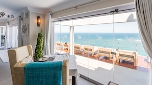 A balcony with a view of the sea, a dining table with chairs, and a sofa.