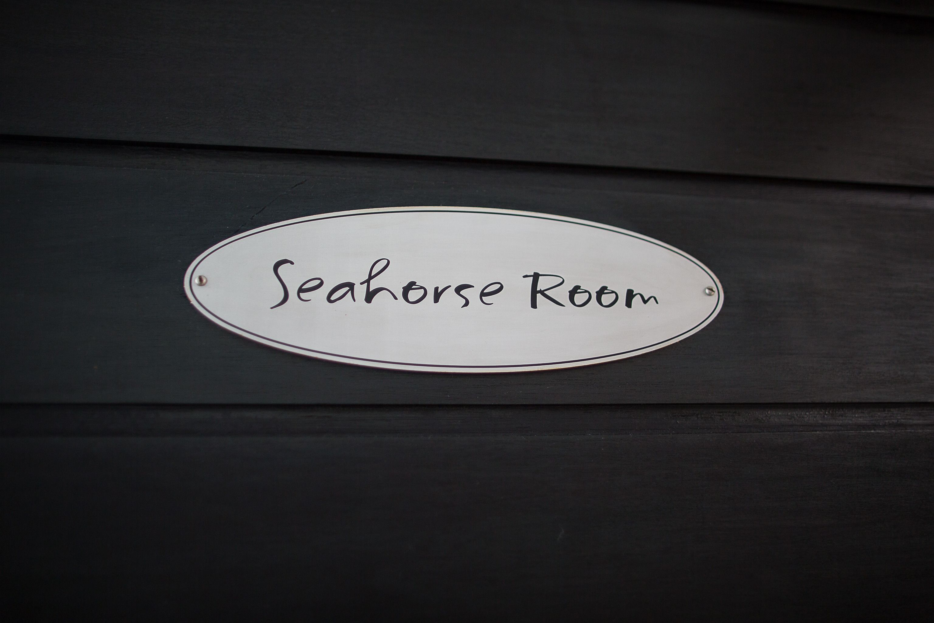 A sign labeled "Seahorse Room" on a dark wooden surface.