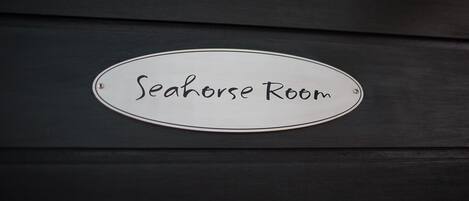 A sign labeled "Seahorse Room" on a dark wooden surface.