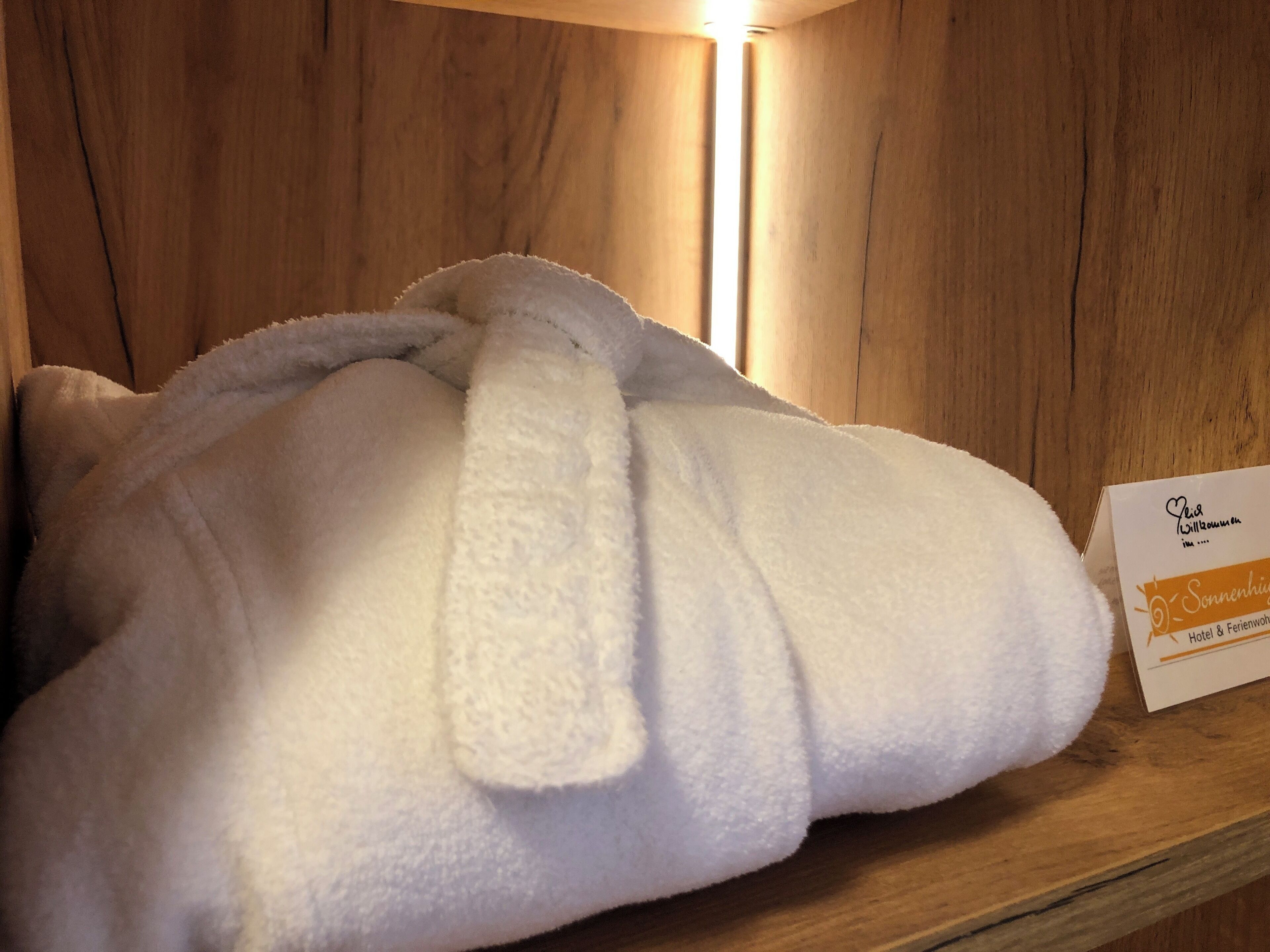 A white bathrobe on a wooden shelf with a sign indicating a hotel and restaurant.