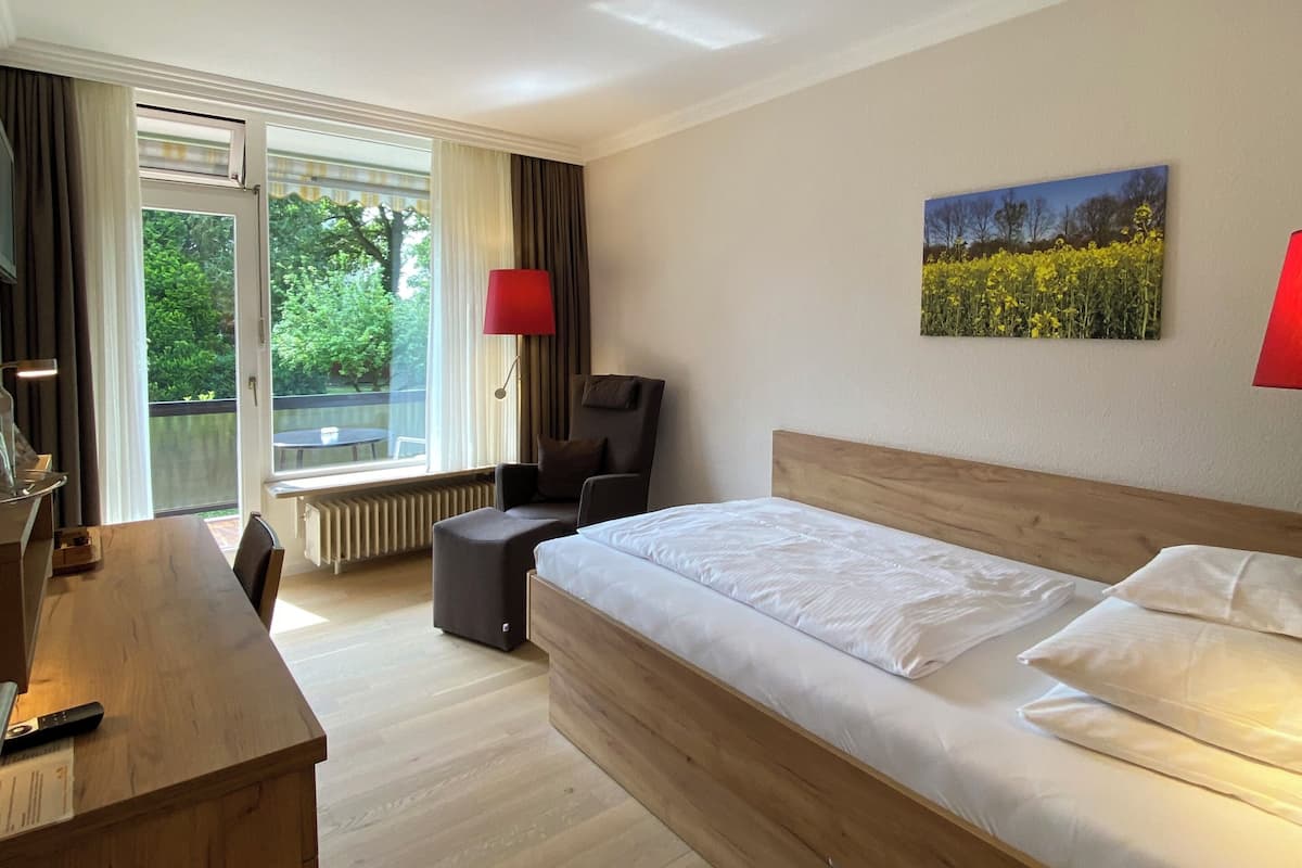 Une chambre d’hôtel avec un grand lit, un bureau, une chaise, une lampe rouge et un tableau au mur.