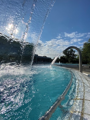 Une piscine à l’eau claire, agrémentée d’une fontaine et dotée d’une terrasse carrelée.