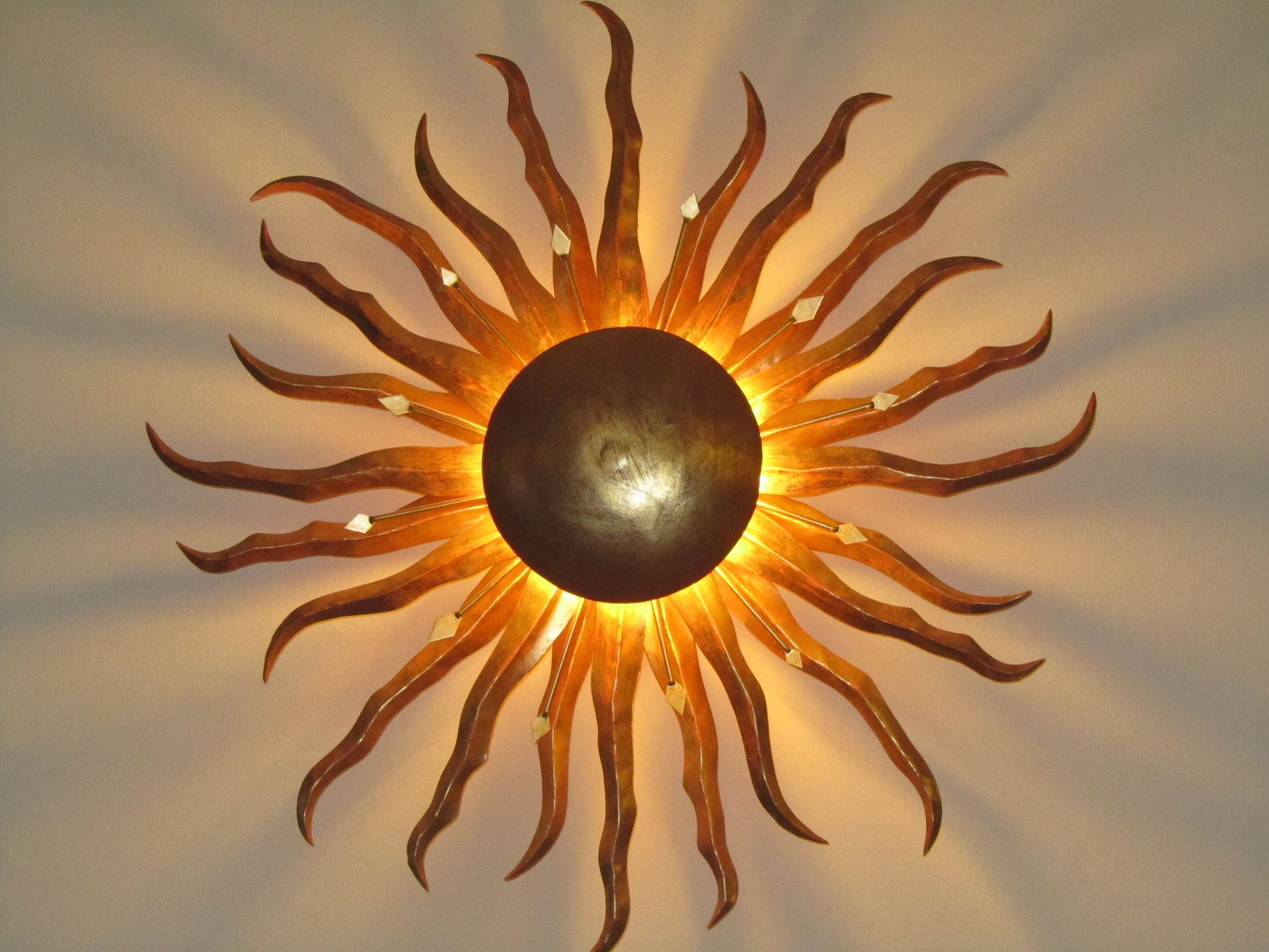 A sun-shaped wall decoration with a central sphere and radiating elements.