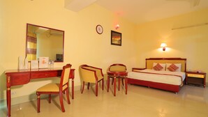 A hotel room with a bed, desk, chairs, a mirror, a clock, and a wall-mounted lamp. - Hotel Metro International (Sylhet)