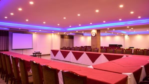 A conference room with a long table, chairs, a projector screen, and a clock on the wall. - Hotel Metro International (Sylhet)