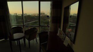 A room with a large window, two chairs, a small table, and a mirror. - Hotel Metro International (Sylhet)