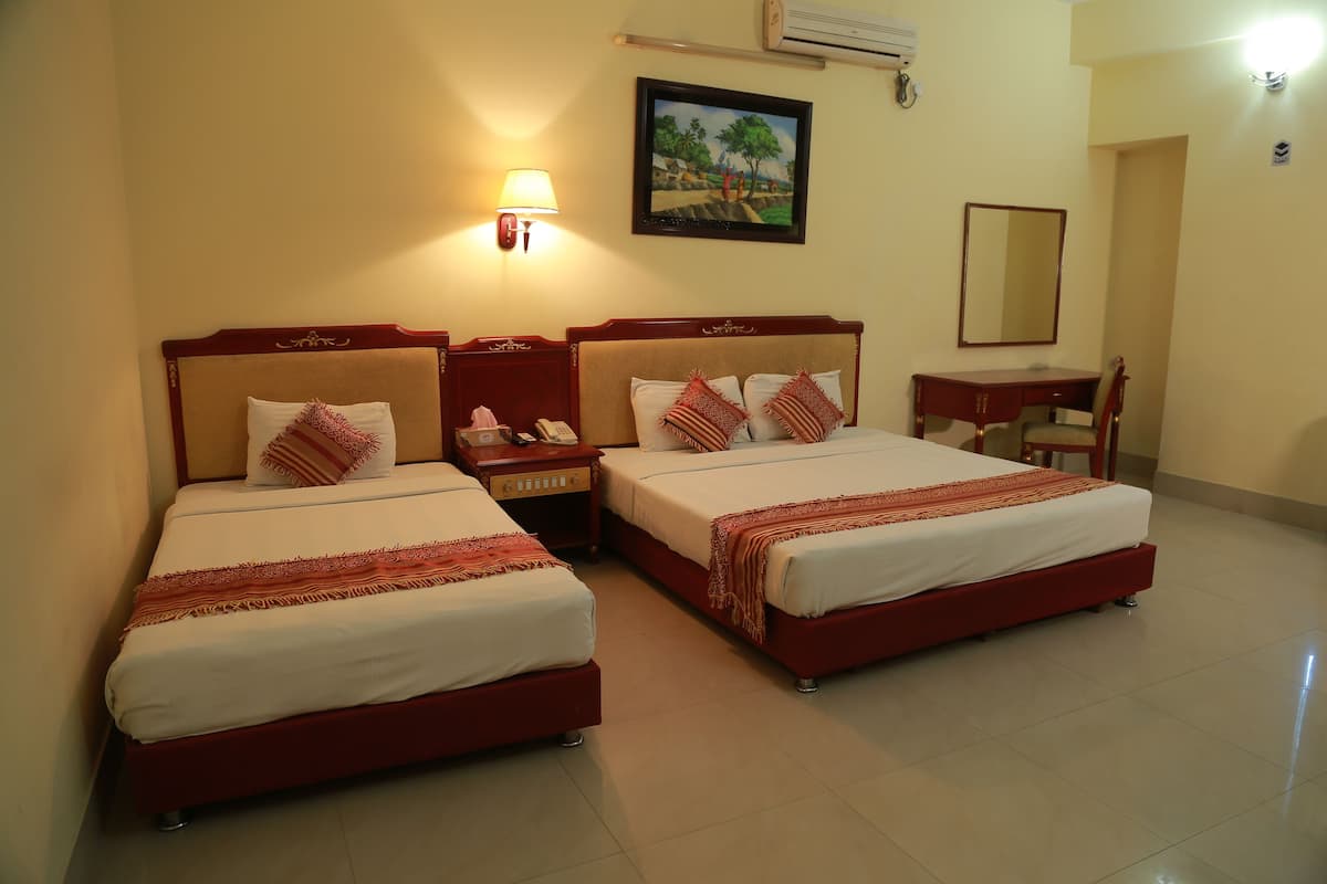 A hotel room with two single beds, a desk, a chair, a bedside table, a lamp, and a painting on the wall.