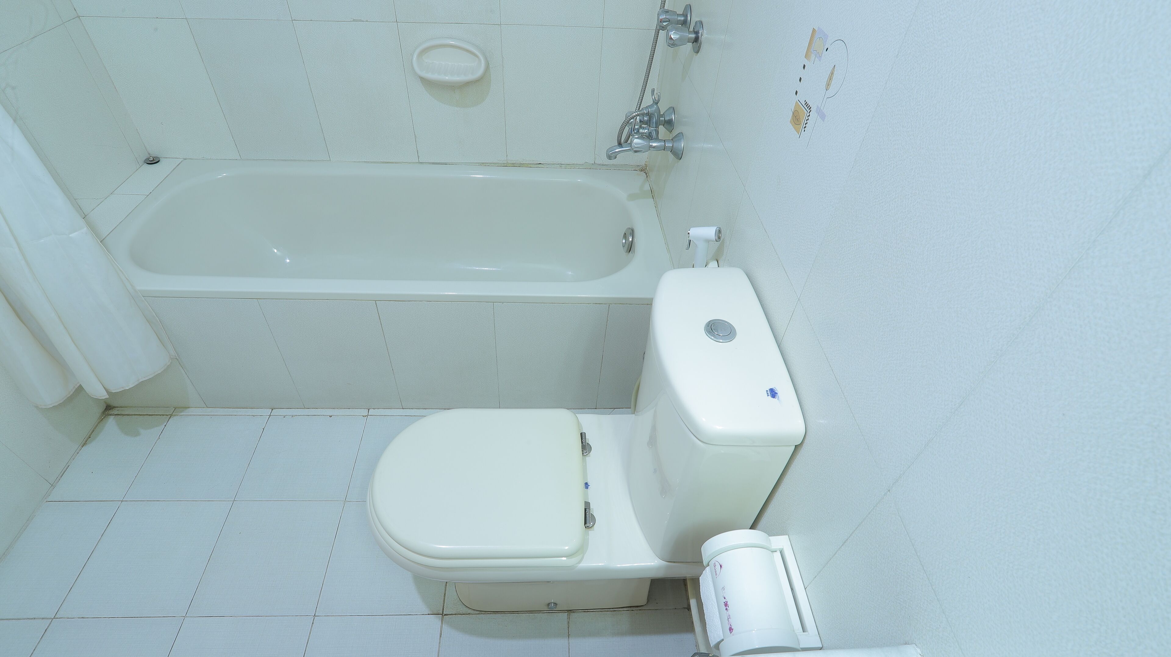 Un baño pequeño y blanco con bañera, inodoro y secamanos.