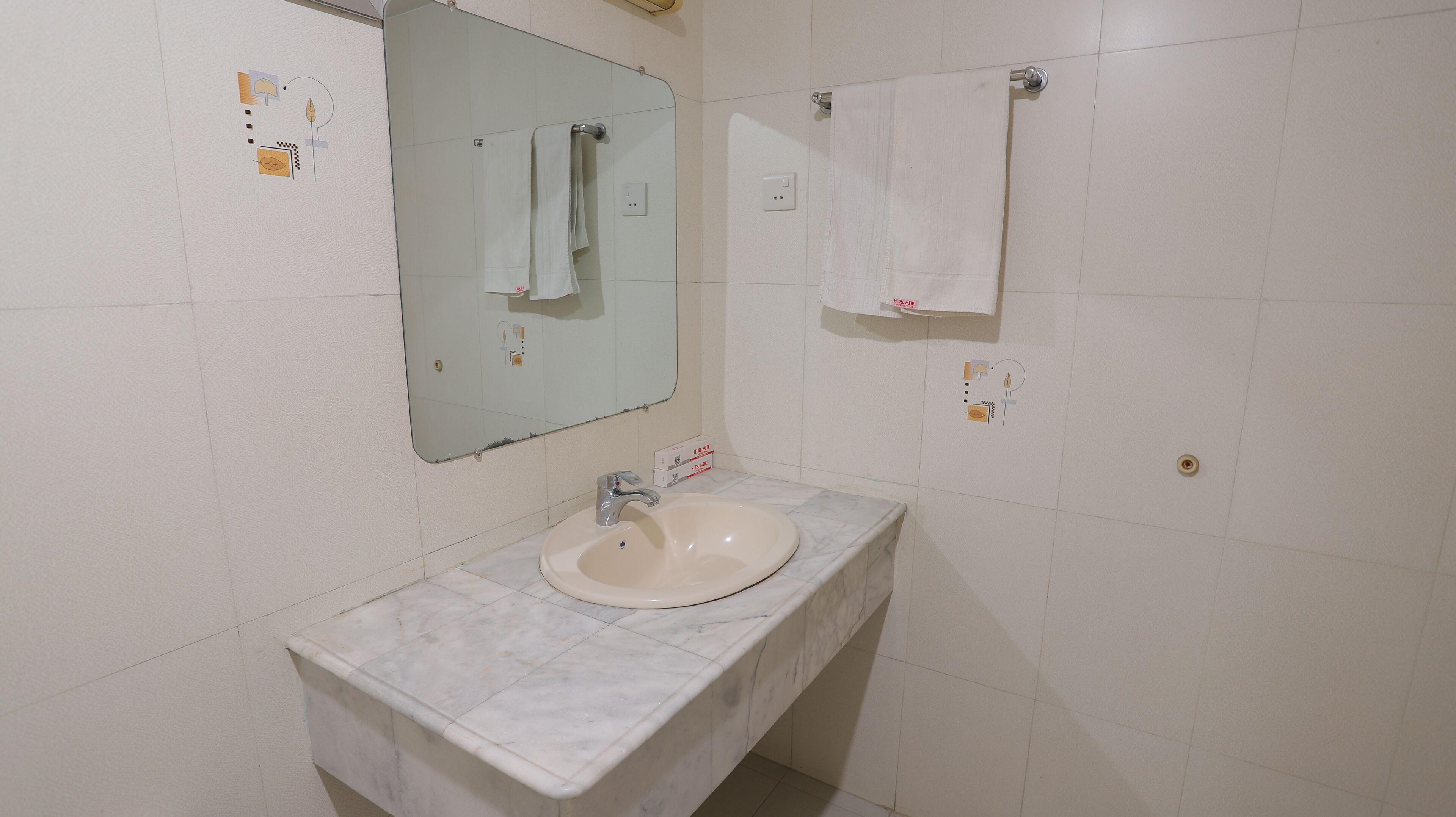 Un baño con lavamanos de mármol, un espejo y una toalla colgada en la pared.