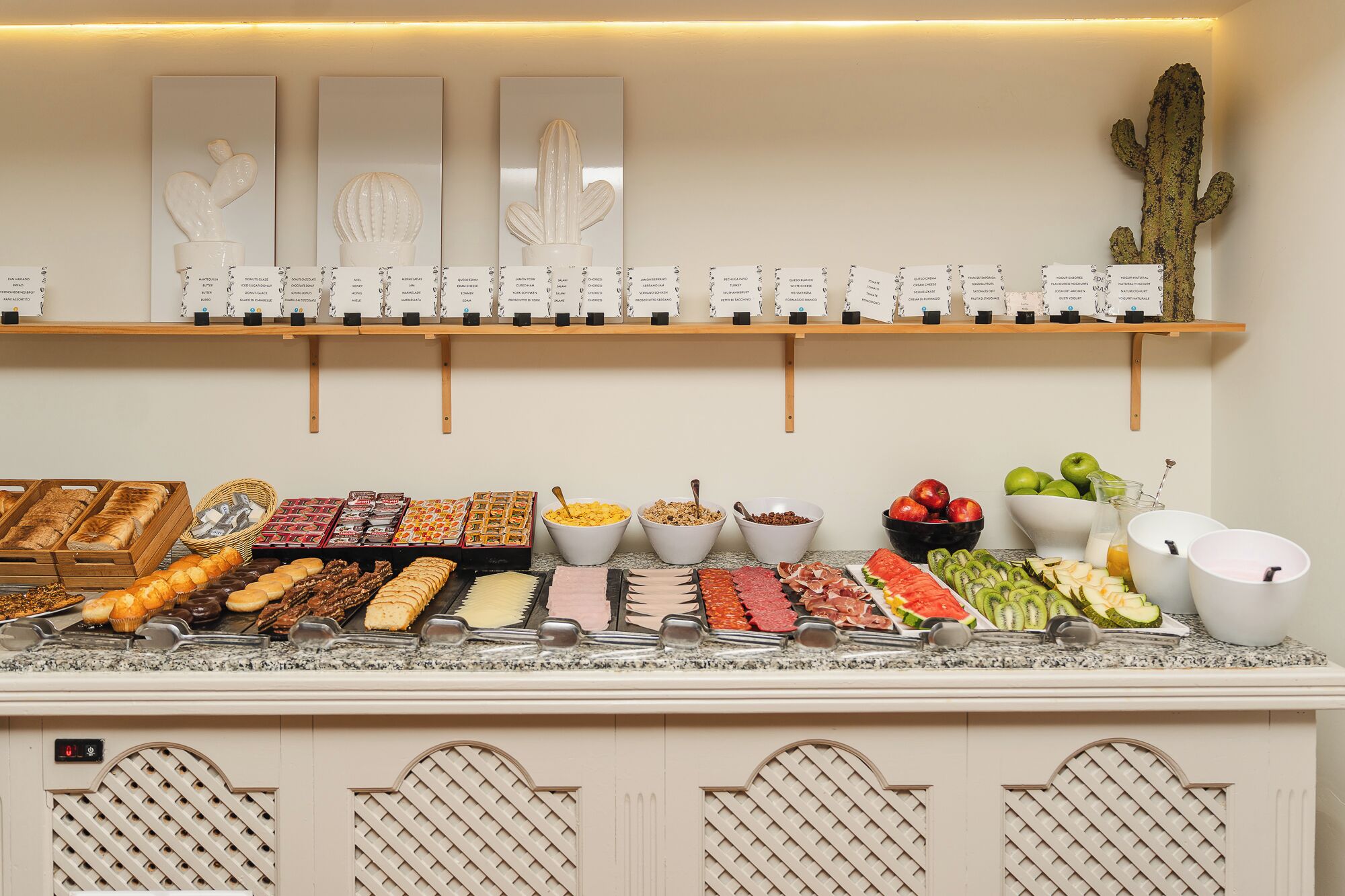 A buffet with various food items and a cactus decoration on the wall.