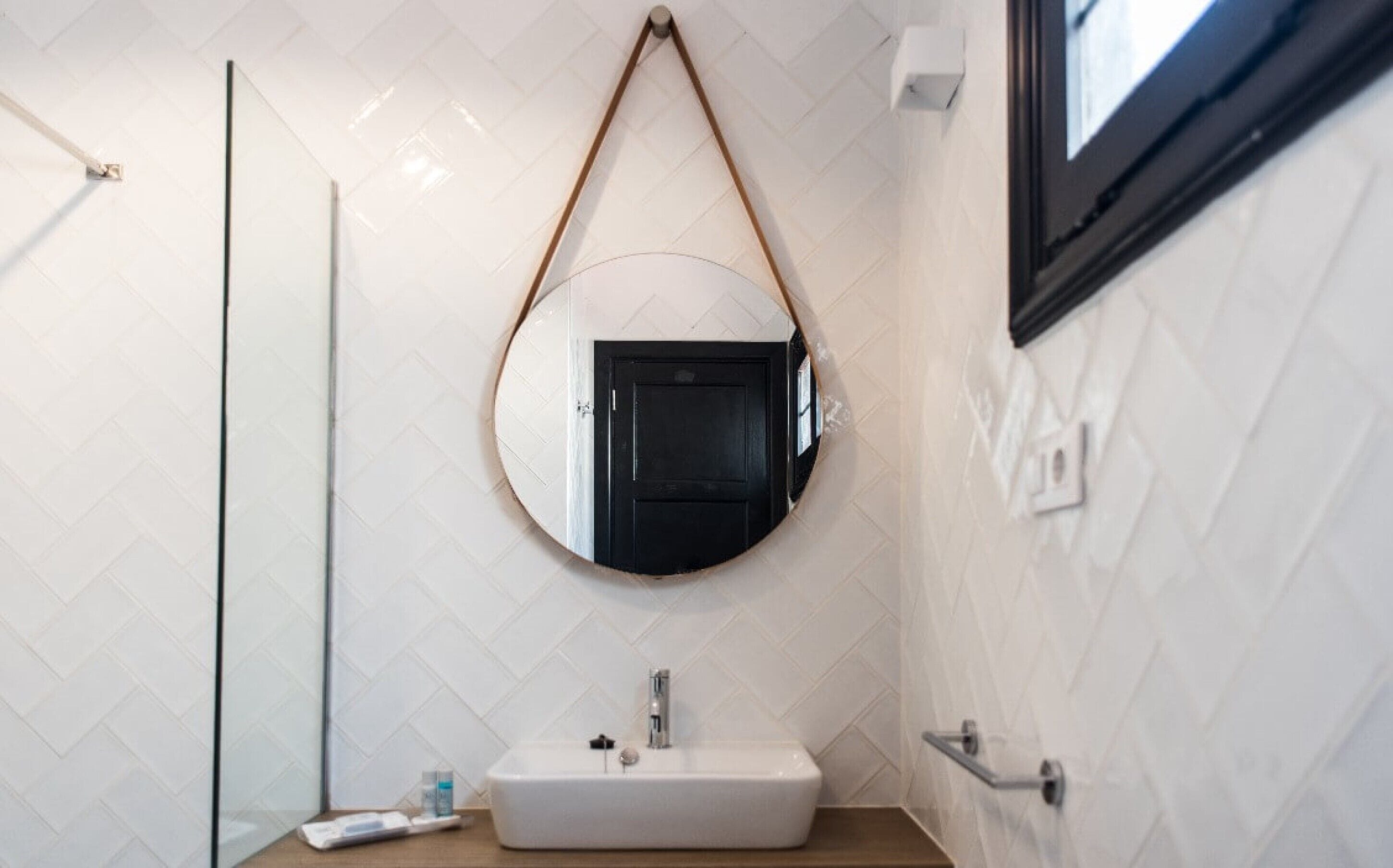 A bathroom with a white sink, a mirror, and a glass shower enclosure.