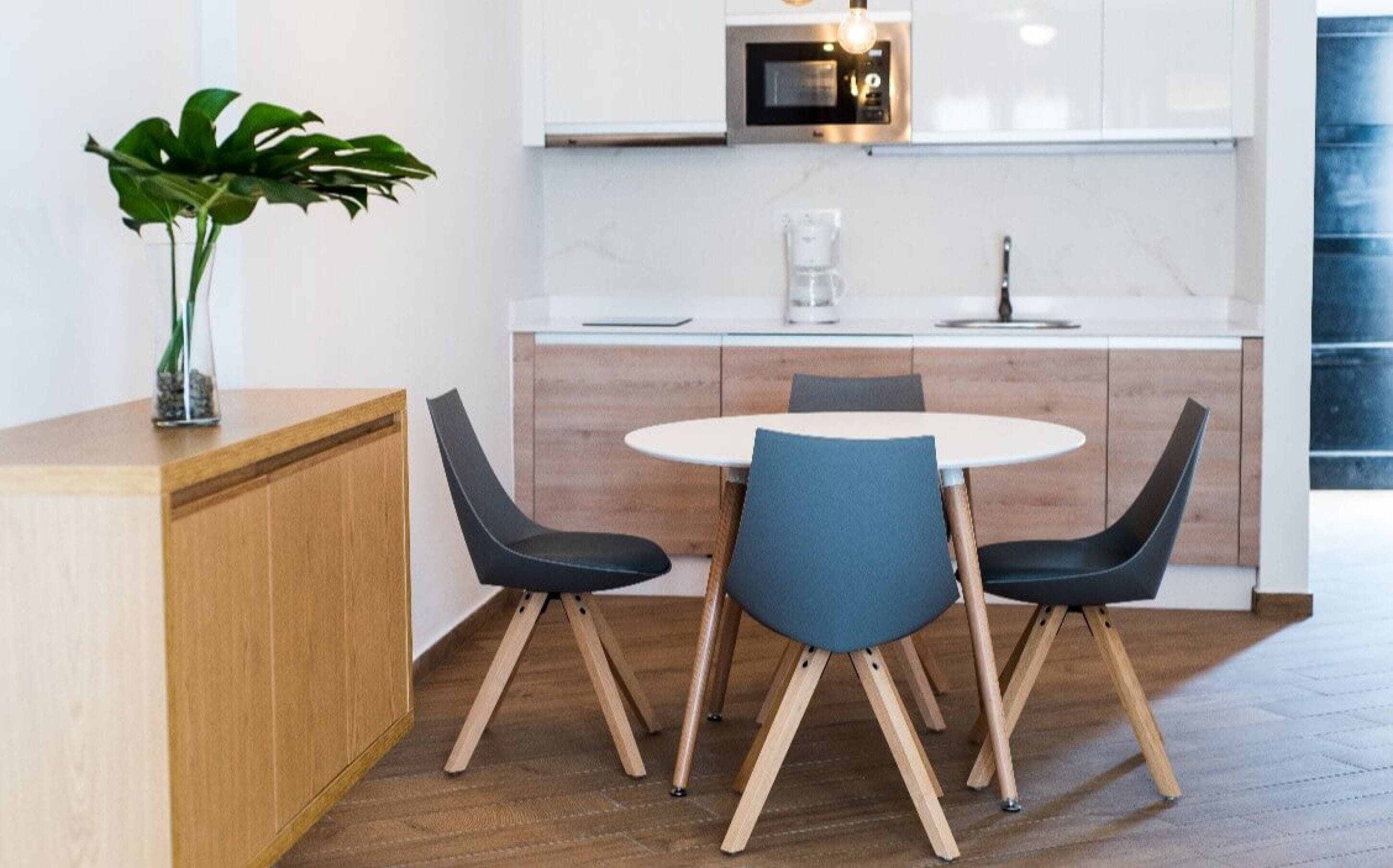 Une cuisine moderne avec une table de salle à manger ronde, deux chaises et une plante en pot.